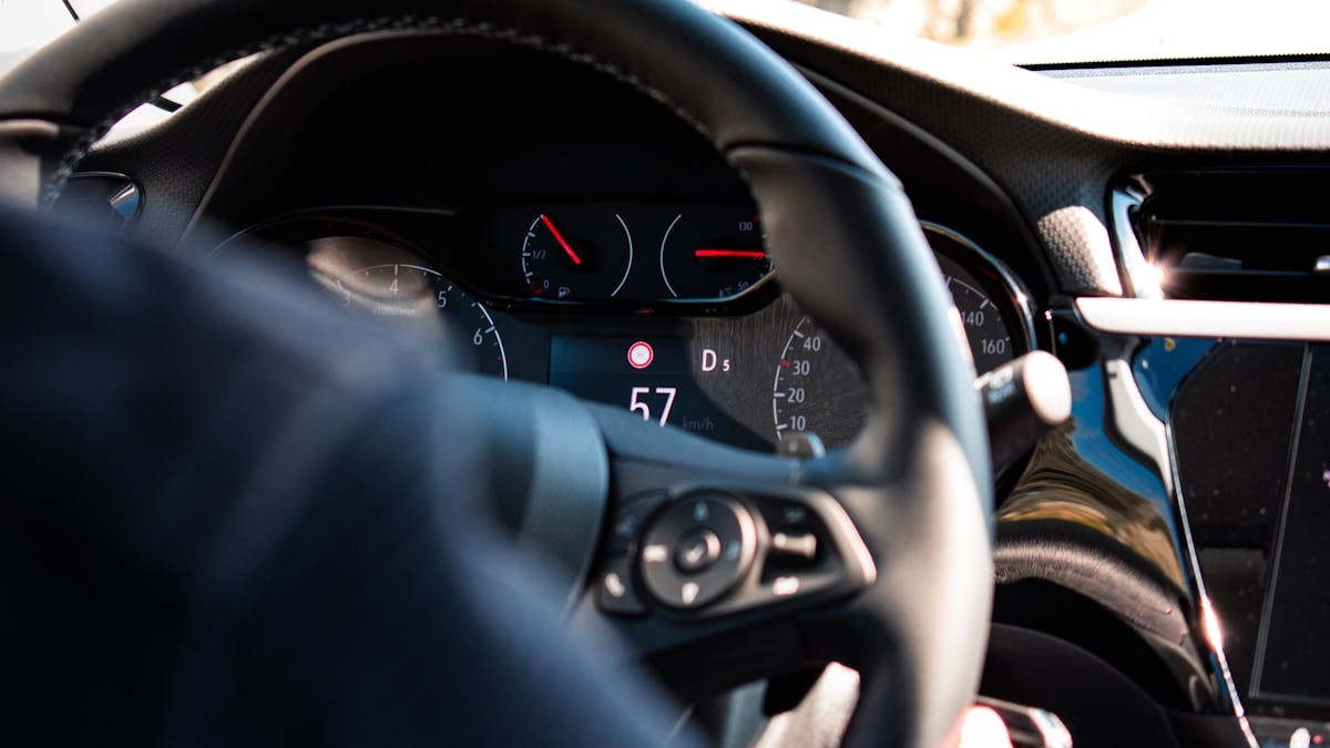 Close-up view of a car dashboard and steering wheel, featuring a digital speedometer display.